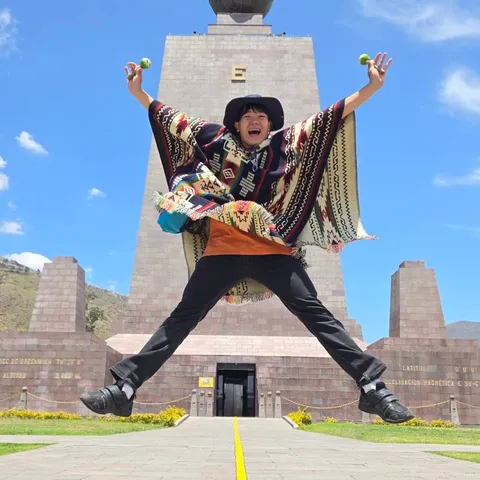 エクアドルの赤道記念碑の前でジャンプするたーとる